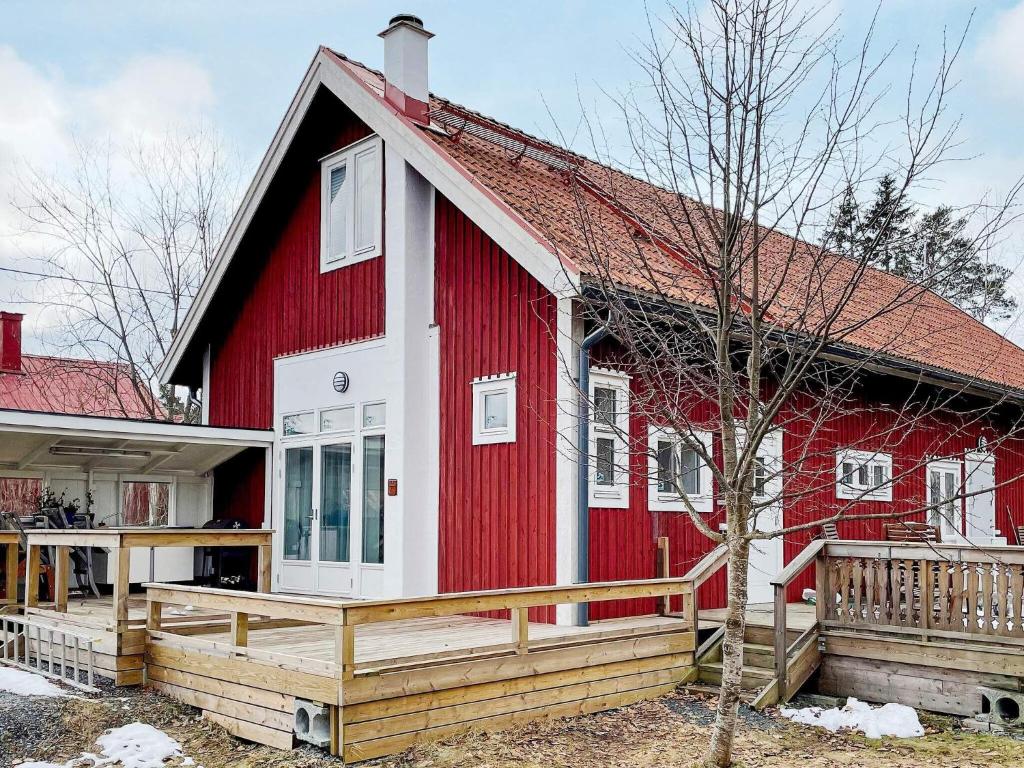 Holiday home VÄDDÖ V في Väddö: بيت احمر وبيض وسطح خشبي