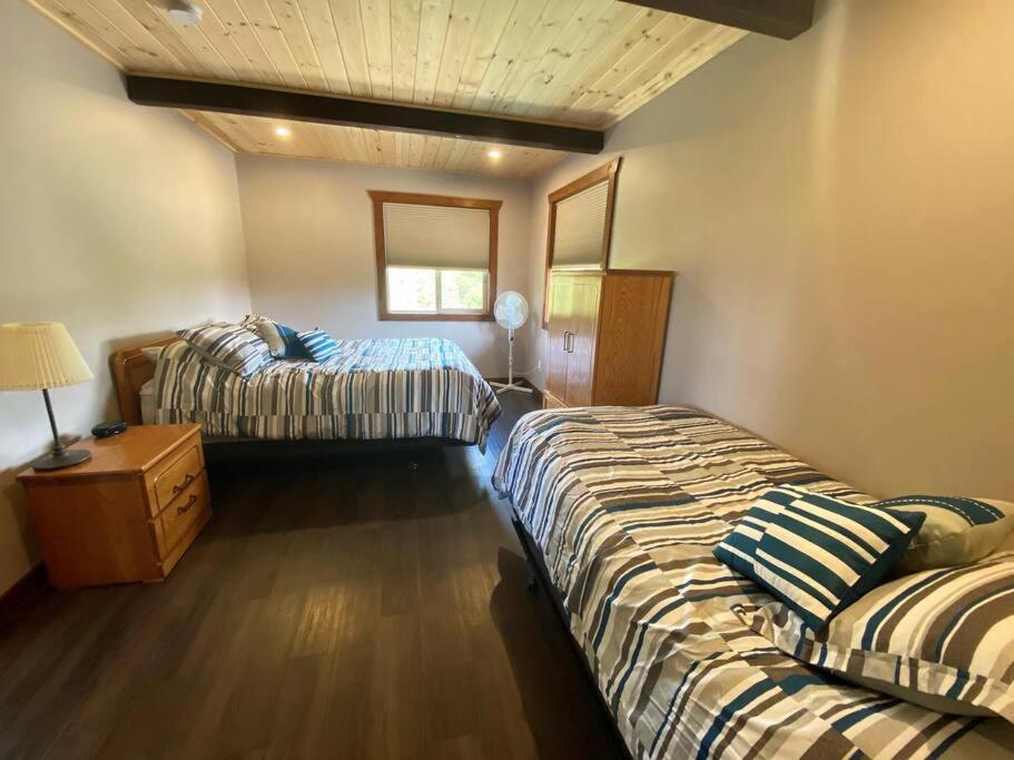 1 dormitorio con 2 camas y mesa con lámpara en The Westview Cabin en Valemount