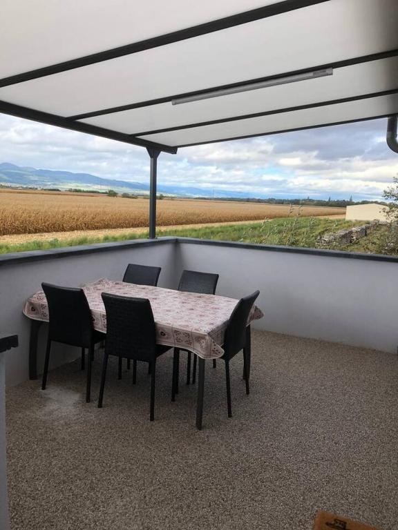 d'une table et de chaises sur un balcon avec vue sur un champ. dans l'établissement Maison charmante à Munwiller avec terrasse et parking gratuit., à Munwiller