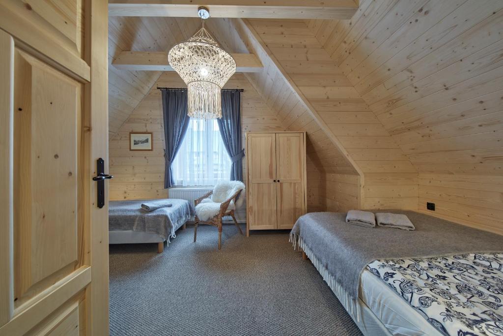 un dormitorio en el ático con 2 camas y una lámpara de araña en Chochołóvka, en Chochołów