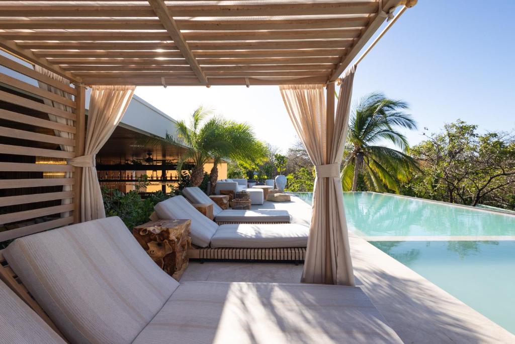 un patio al aire libre con sofá y sillas junto a una piscina en Silvestre Nosara Hotel & Residences, en Nosara