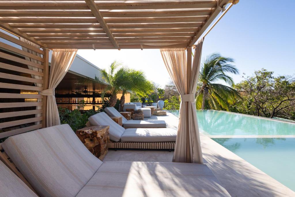 un patio al aire libre con sofá y sillas junto a una piscina en Silvestre Nosara Hotel & Residences en Nosara