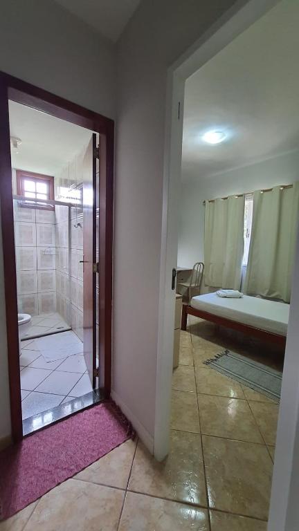 a room with a bathroom with a shower and a bed at Pousada Alto Riviera in Macaé