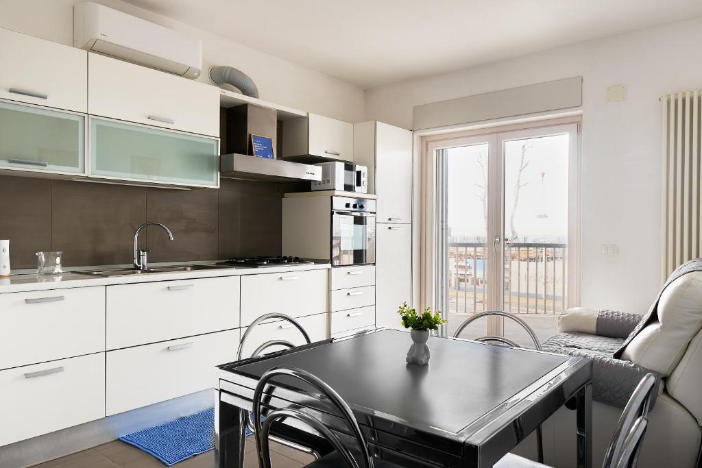 una cucina con armadi bianchi e tavolo con sedie di Nuovissimo Appartamento con Terrazza vista Mare a Francavilla al Mare