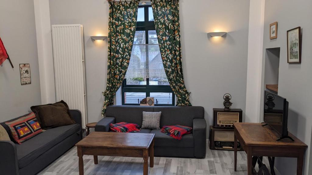 un salon avec un canapé et une fenêtre dans l'établissement APPART' DU CHEF DE GARE gîte à Gouarec au pied de la Vélodyssée, à Gouarec