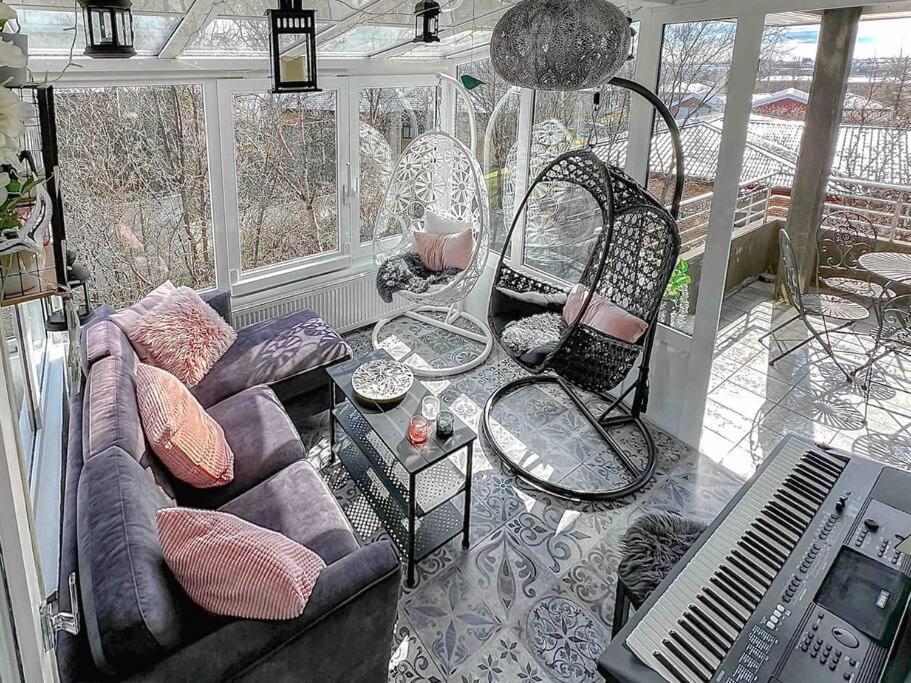 uma sala de estar com um sofá e cadeiras num alpendre em Family friendly home close to golden circle and to city central! em Reykjavík