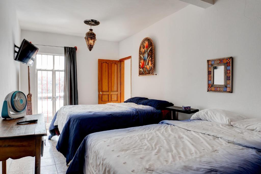 瓜納華托的住宿－Casa Palaxs，一间卧室设有两张床、一张桌子和一个窗口。