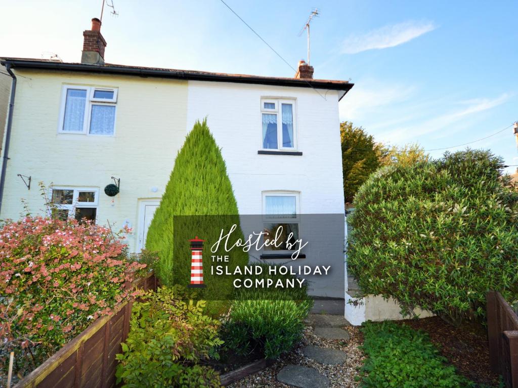 ein weißes Haus mit einem Schild, das die Insel-Urlaubsgesellschaft liest in der Unterkunft Charnwood Cottage in Brading