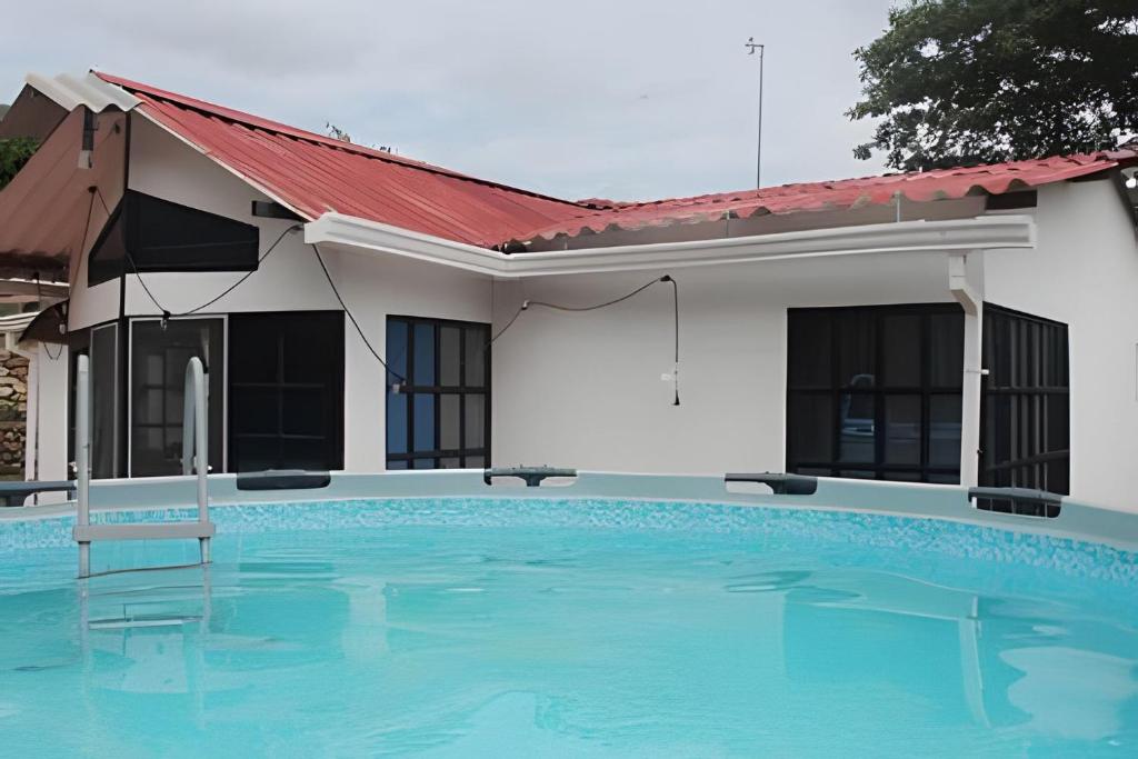 una piscina frente a una casa en Cabaña Campestre de con piscina, cocina, y wifi., en Carmen de Apicalá