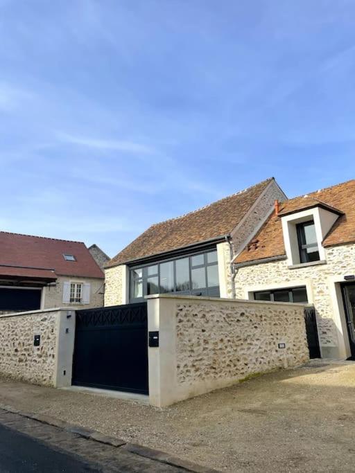 une grande maison avec un mur de pierre devant elle dans l'établissement Les logis du Parc, à Bullion