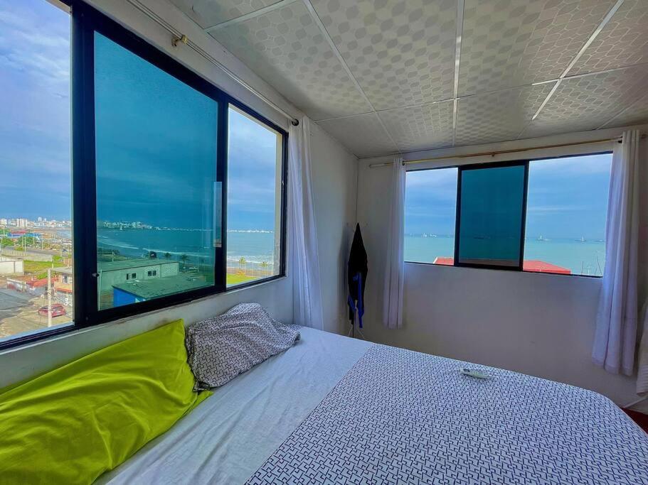 a bedroom with a bed and two large windows at Departamento Suite frente al Mar in Manta