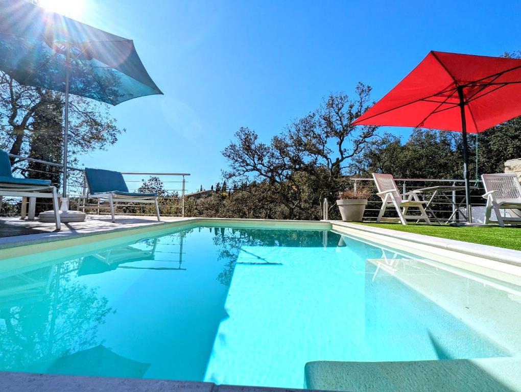 uma piscina com um guarda-sol vermelho e cadeiras em The Villa Capitou em Fréjus