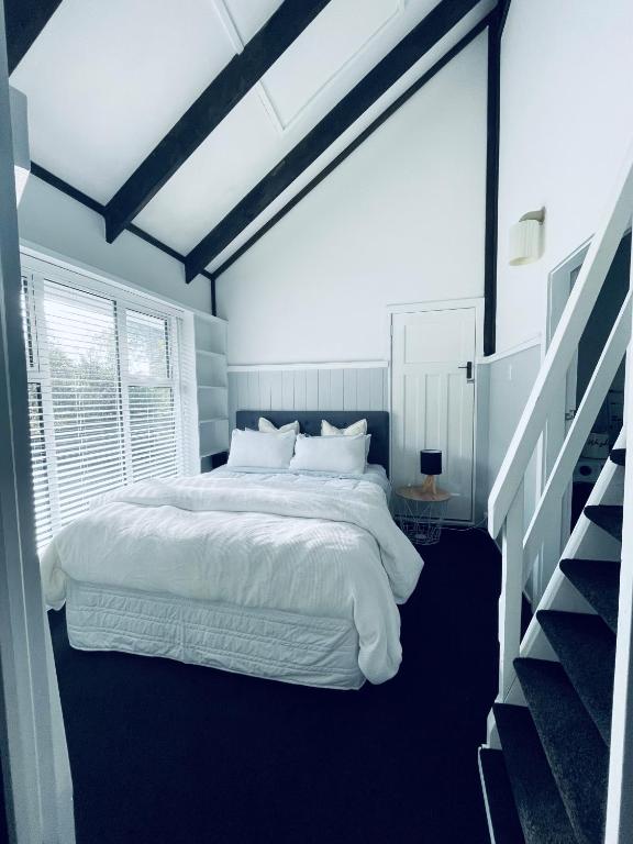a bedroom with a white bed and a staircase at Experience Heritage, Live Modern in Upper Hutt