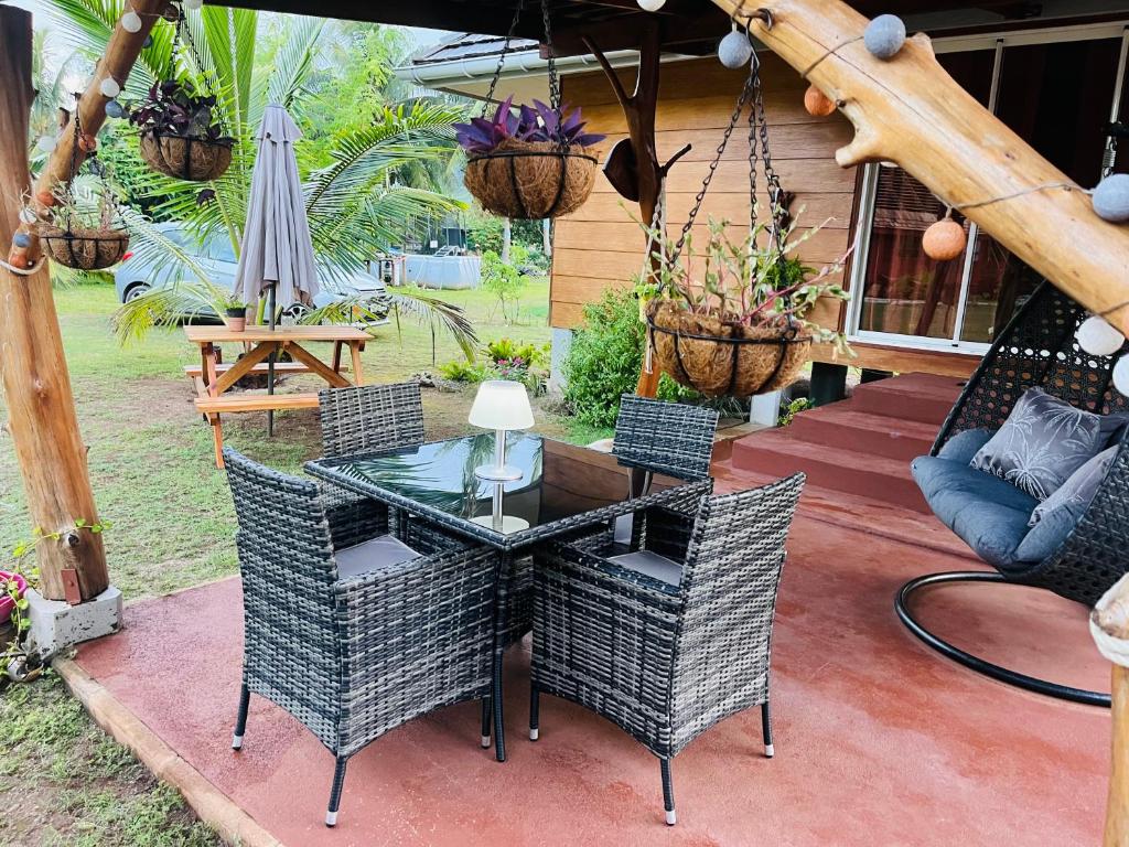 un patio con mesa de cristal, sillas y sombrilla en Bungalow KURA, en Moorea