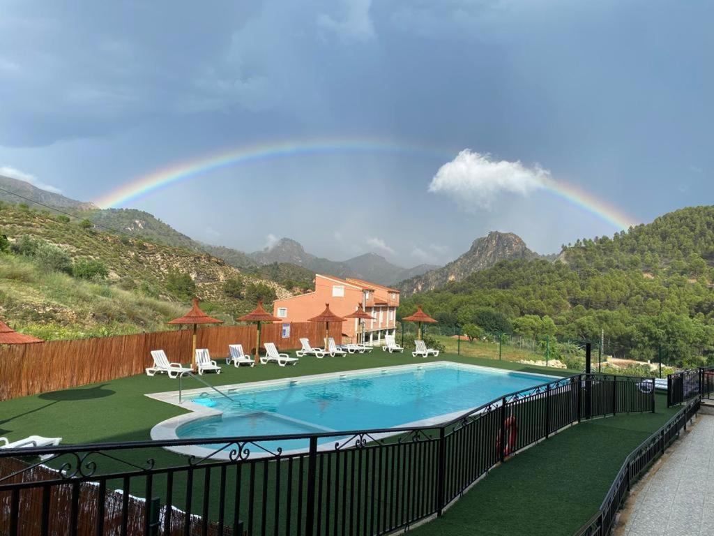 un arco iris en el cielo sobre una piscina en CASA RURAL G, en Elche de la Sierra