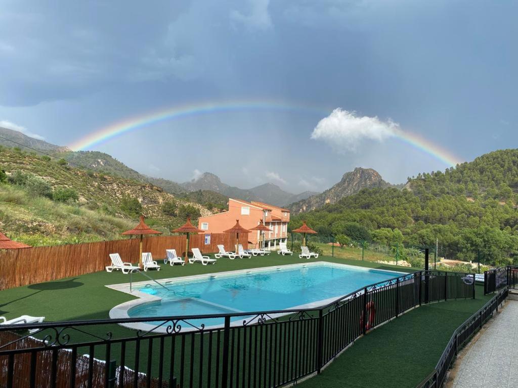 a rainbow in the sky over a swimming pool at Casa Rural Puente del S,egura G in Elche de la Sierra