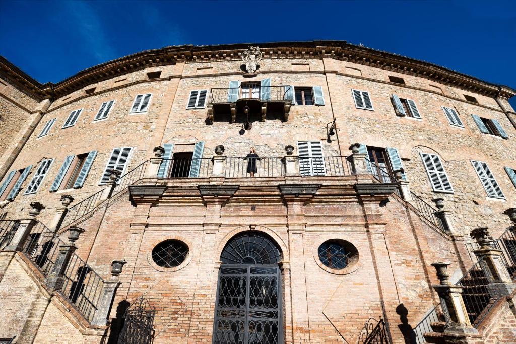 Un grand bâtiment en briques avec un balcon est disponible. dans l'établissement Castello di Sovicille - Residenza d'Epoca, à Sovicille