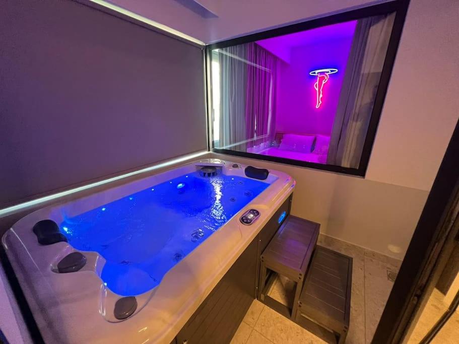 El baño incluye una gran bañera azul con luz púrpura. en BlueMotion - ArteSuite, en Pireo