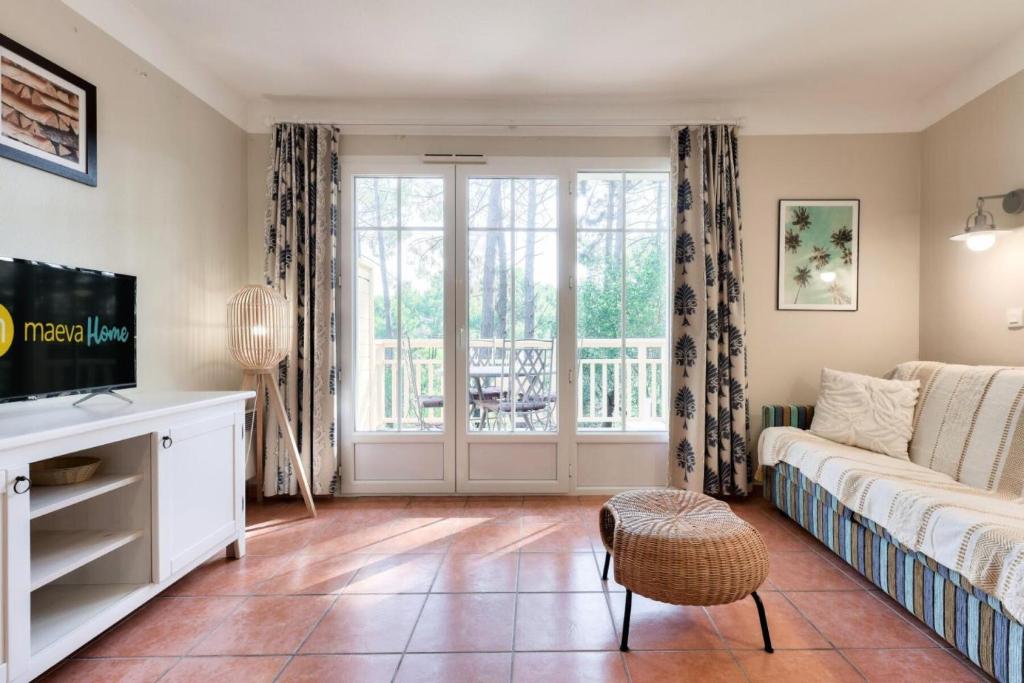 un salon avec un canapé et une télévision dans l'établissement Résidence Lacanau Les Pins - maeva Home - Appartement 2 Pièces 4 Personnes - Sélection MAE-6514, à Lacanau