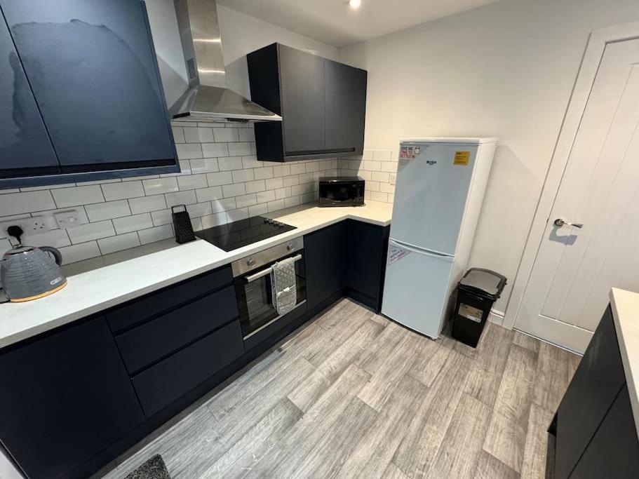 a kitchen with black cabinets and a white refrigerator at Brand new refurb 8 person house in Hull