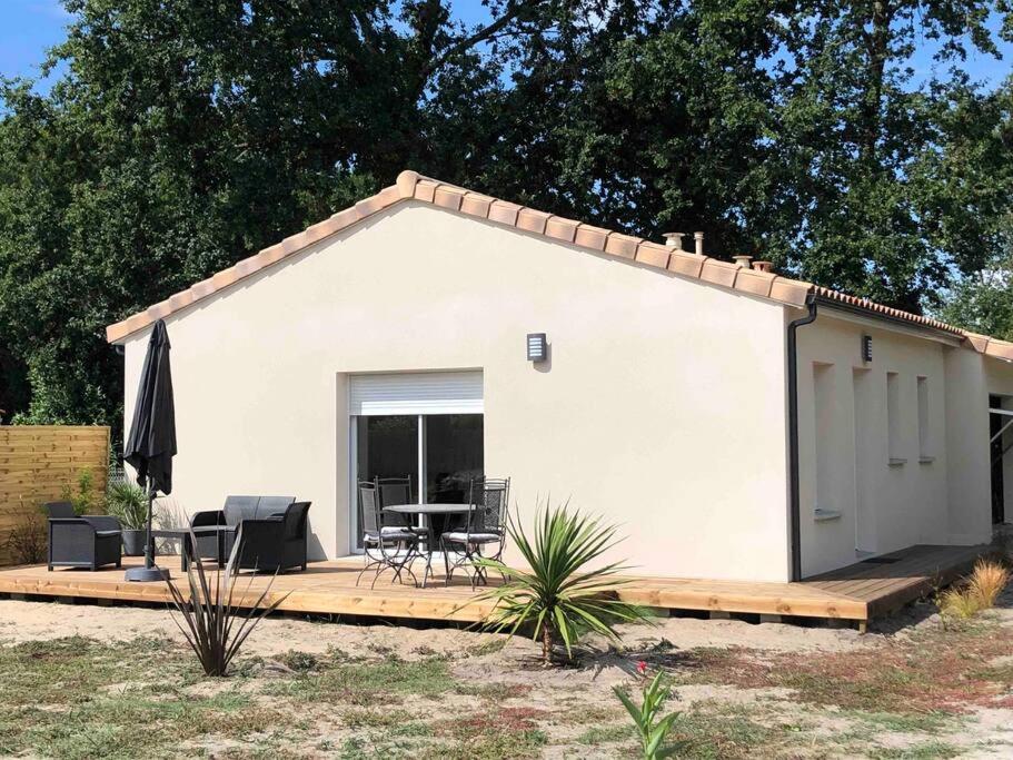 ein kleines weißes Haus mit einem Tisch und Stühlen in der Unterkunft Jolie maison à 5 min de l'océan in Grayan-et-lʼHôpital