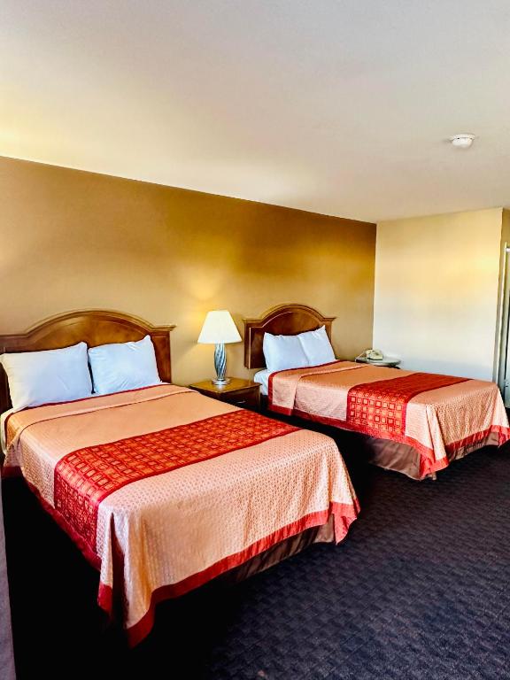 a hotel room with two beds with red sheets at Franciscan Inn Motel in Vista