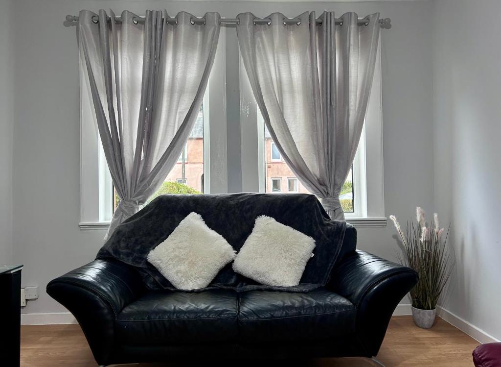 a black leather couch with two pillows in front of a window at Urban Oasis:perfect stay in city in Edinburgh