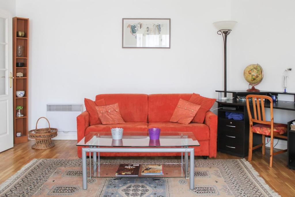 een woonkamer met een rode bank en een tafel bij Bright and quiet apartment with unobstructed view in Boulogne-Billancourt