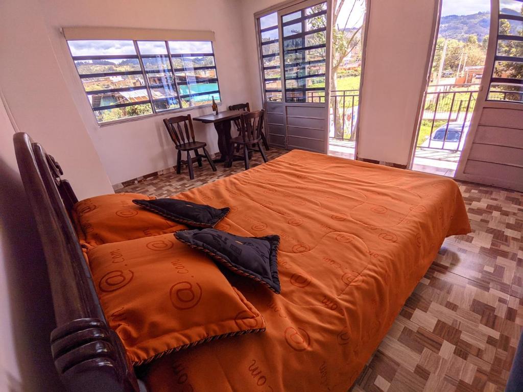 a bedroom with an orange bed and a table with chairs at Vivienda Rural La Estancia in Duitama