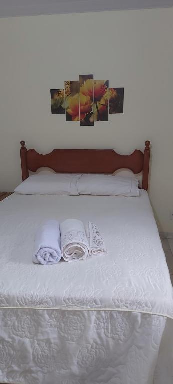 Una cama con sábanas blancas y dos toallas. en Recanto Casa Amarela de São Romão en Nova Friburgo
