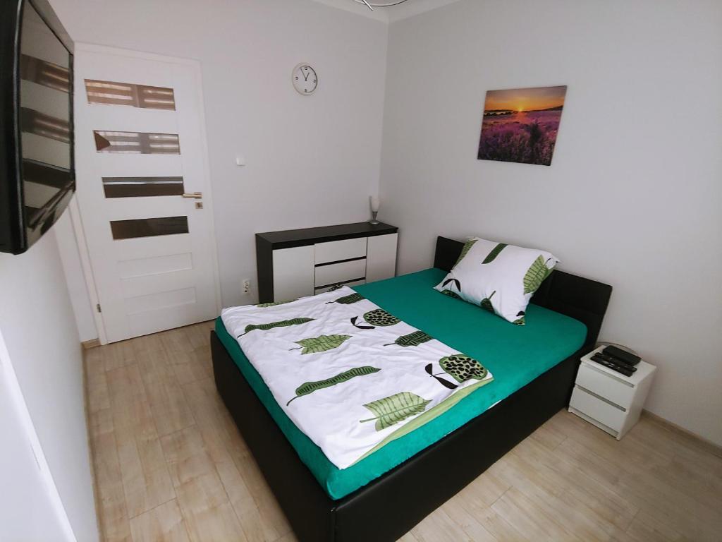 a bedroom with a bed with a green and white comforter at Barbara in Kalisz