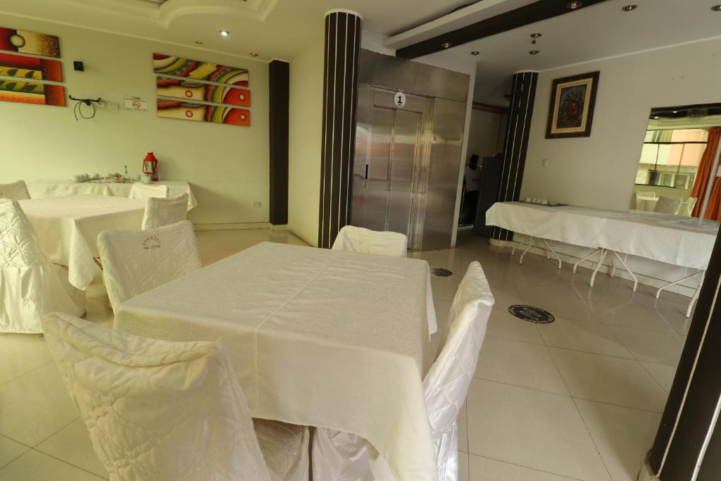 una sala da pranzo con tavoli bianchi e sedie bianche di Hotel Frontera a Tacna