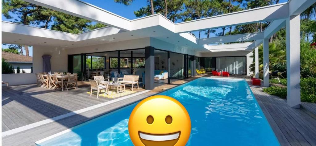 une maison avec une piscine et un visage dans l'établissement Villa CALIFORNIA Piscine chauffée 14x4m Moulleau Abatilles 10 pers, à Arcachon