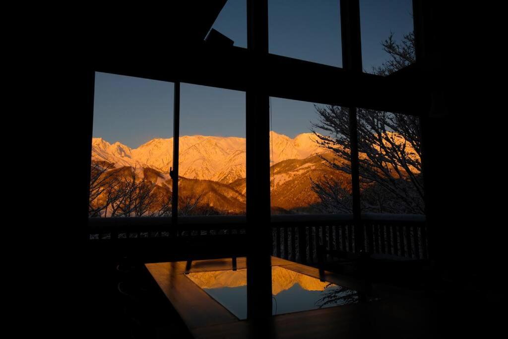a view of a mountain seen through a window at WAKURABA- Chalet with the best views in Hakuba! in Hakuba