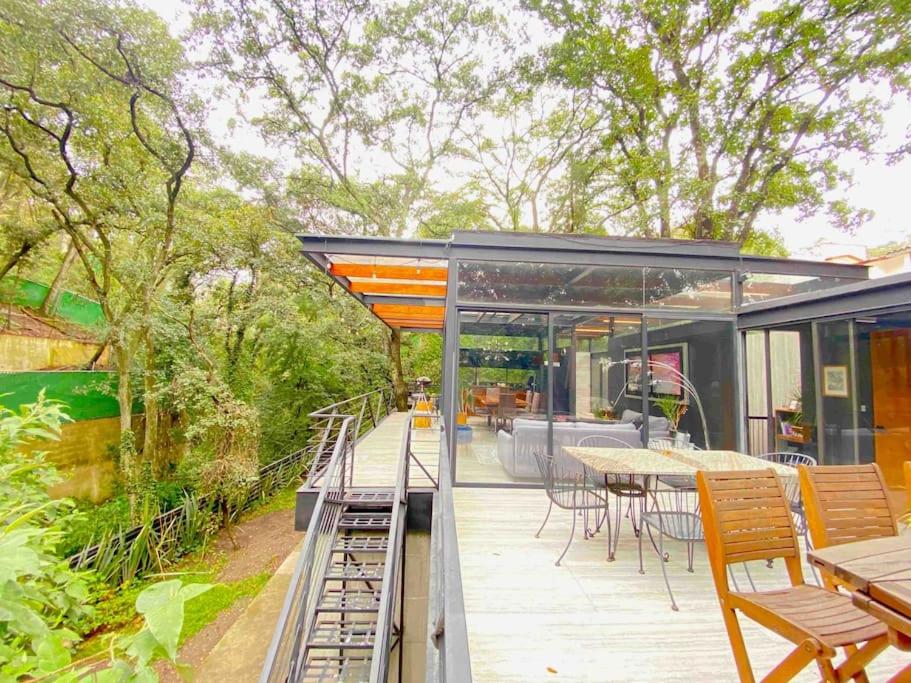 une maison en verre avec une terrasse dotée de tables et de chaises dans l'établissement Casa en el bosque, à Ciudad López Mateos