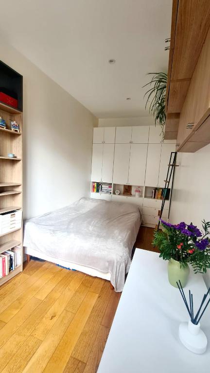 ein Schlafzimmer mit einem Bett und einem Tisch mit Blumen in der Unterkunft Charmant Appartement moderne Paris 13e in Paris