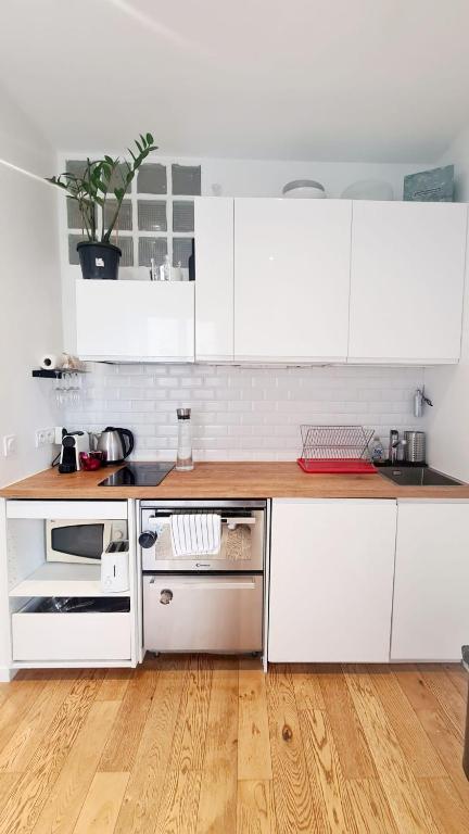 eine Küche mit weißen Schränken und Holzböden in der Unterkunft Charmant Appartement moderne Paris 13e in Paris