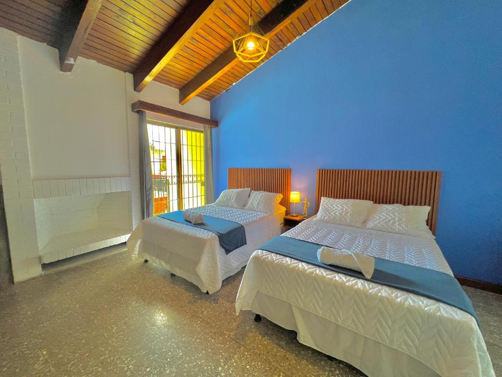 a bedroom with two beds and a blue wall at Hotel Citadin Z10 in Guatemala