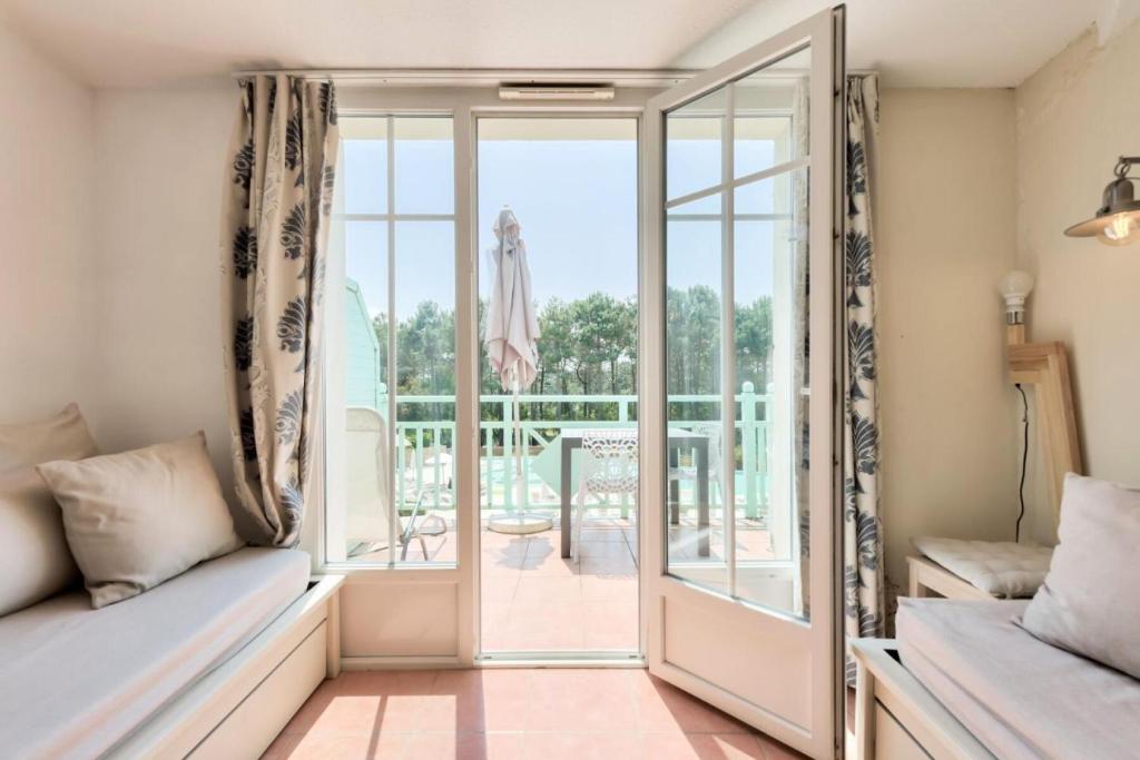 un salon avec un canapé et une porte coulissante en verre dans l'établissement Résidence Lacanau Les Pins - maeva Home - Appartement 2 pièces 5 personnes - Prestige MAE-4844, à Lacanau