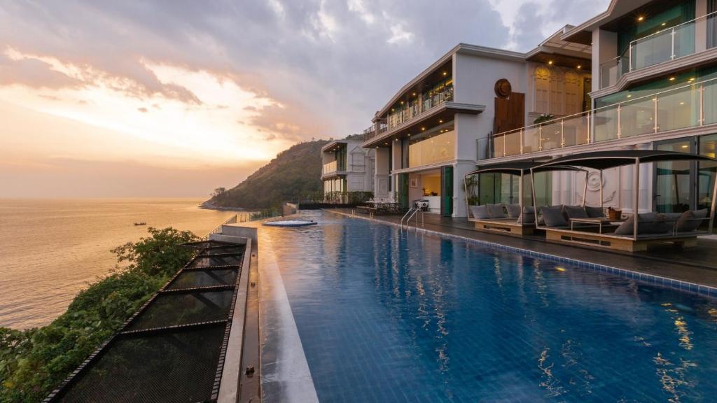 a hotel swimming pool with the ocean in the background at Villa Thousand Cliffs in Nai Harn Beach