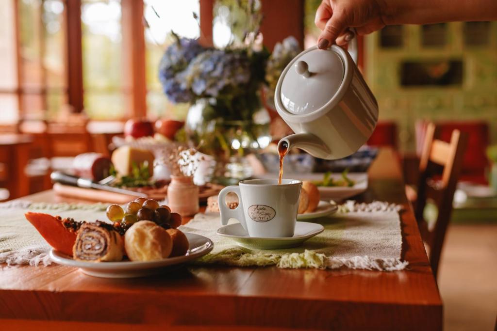 a person pouring coffee into a cup on a table at Afeto Pousada in Bento Gonçalves