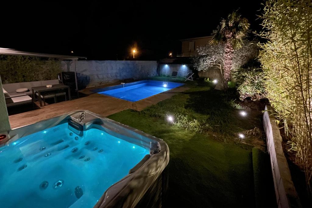 a swimming pool in the middle of a yard at night at Unique! jacuzzi privé 35°C + cinéma Villa entière in Meyzieu