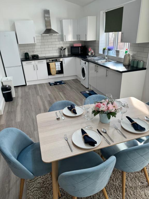 eine Küche mit einem Holztisch und blauen Stühlen in der Unterkunft Spacious 1-Bed Flat Near Wembley Stadium in London