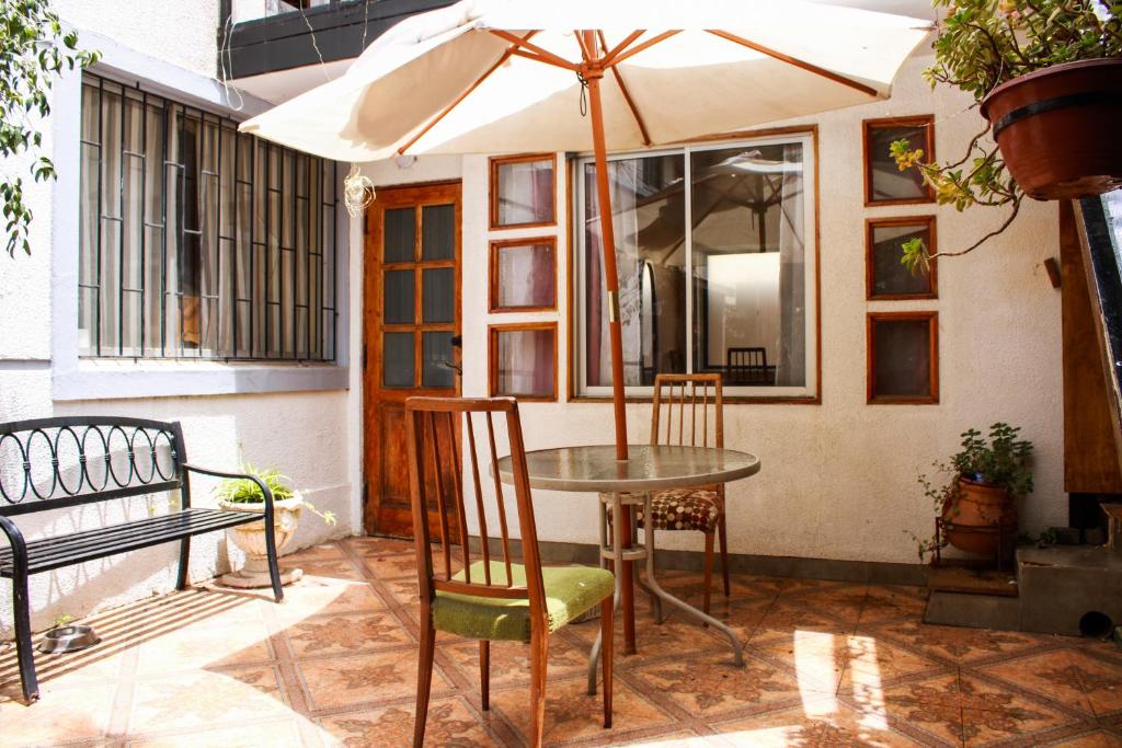 uma mesa e cadeiras com um guarda-sol num pátio em Hostal EntreOrientes em Viña del Mar
