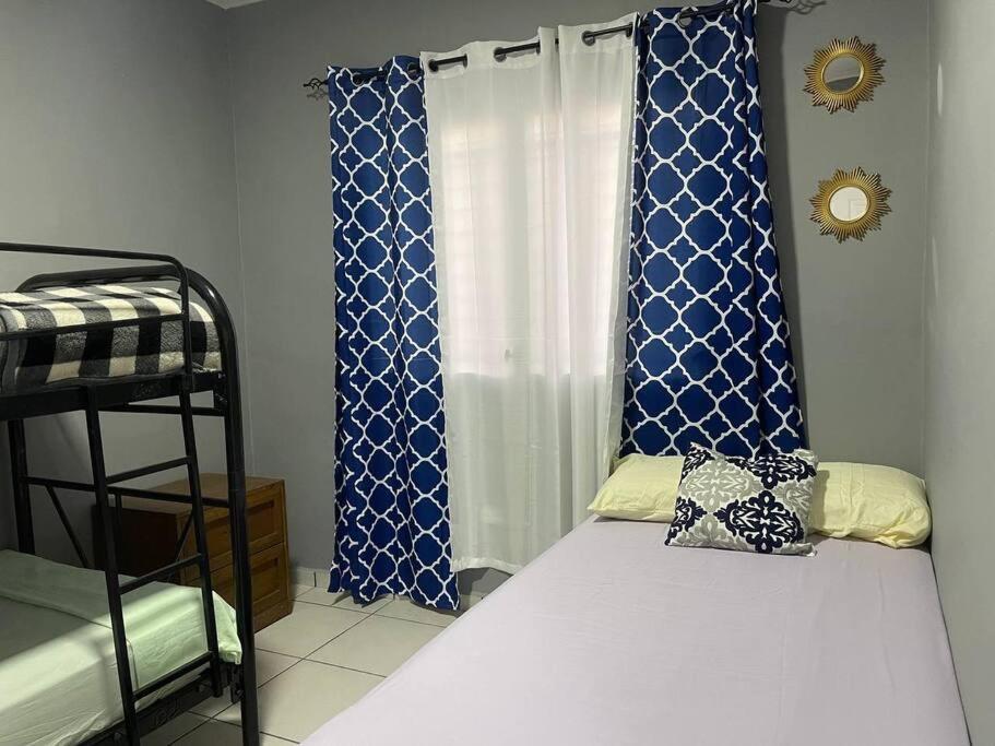 a bedroom with a bed and a window with blue curtains at Casa Residencial Quinta in Comayagua