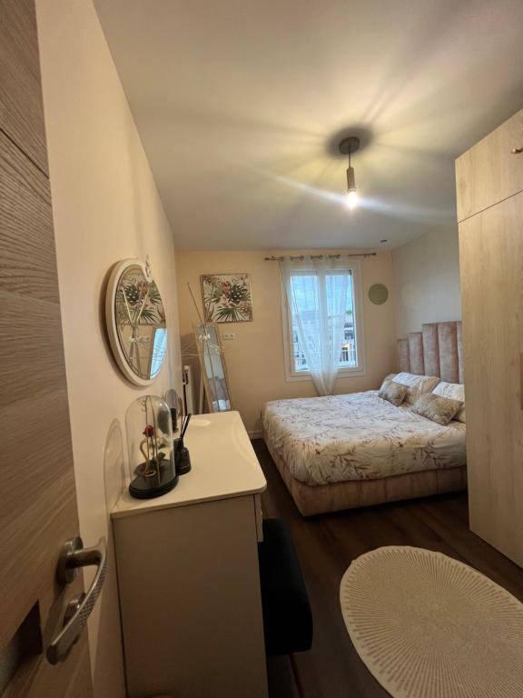 1 dormitorio con cama y mesa con espejo en La veranda du parc, en Issy-les-Moulineaux