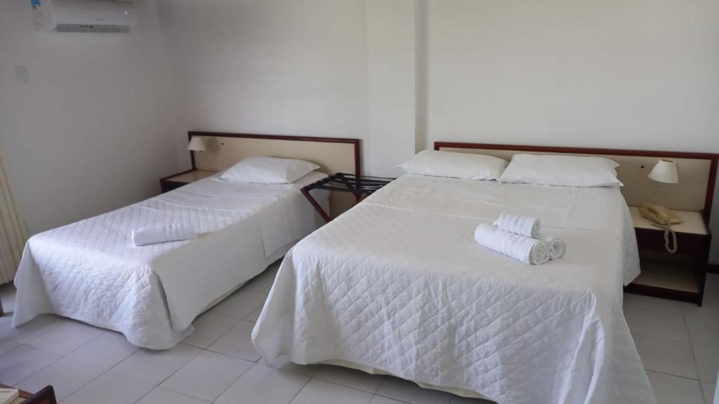 duas camas num quarto com lençóis brancos e toalhas em Quarto 215 do Manos Royal Hotel - propriedade privada em João Pessoa