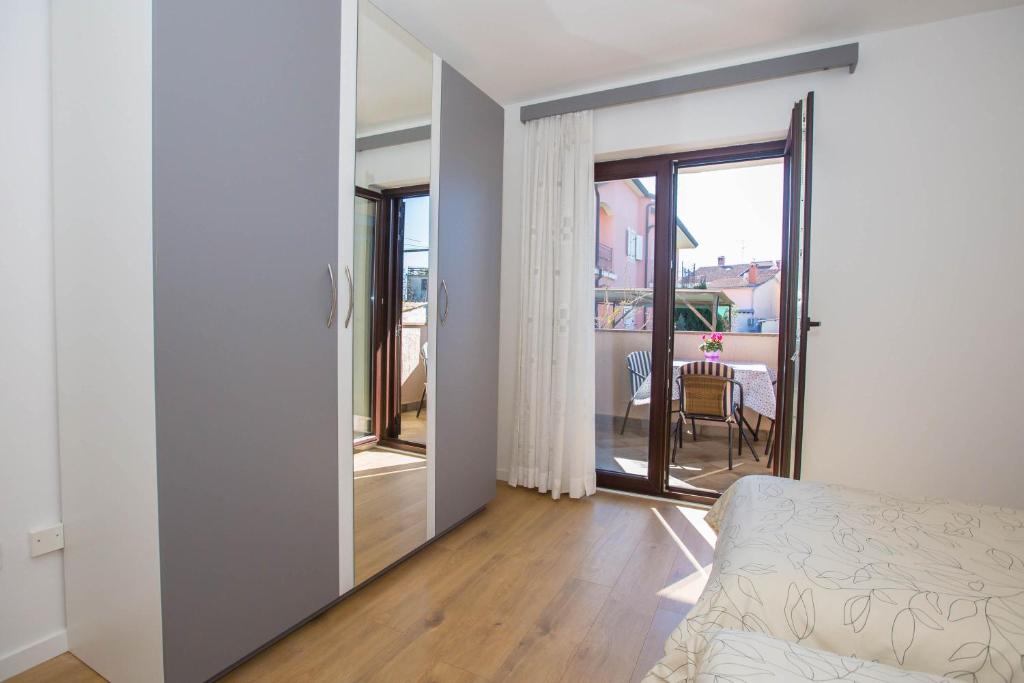1 dormitorio con 1 cama y puerta a un balcón en Apartments Marija, en Funtana