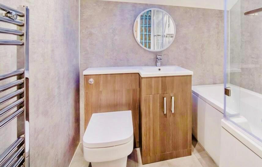 a bathroom with a toilet and a sink and a mirror at Luxury Spacious Apartment in Cardiff