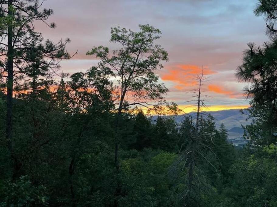um pôr-do-sol no céu sobre uma floresta de árvores em Siskiyou Mountain Place, Ashland em Buckhorn Springs